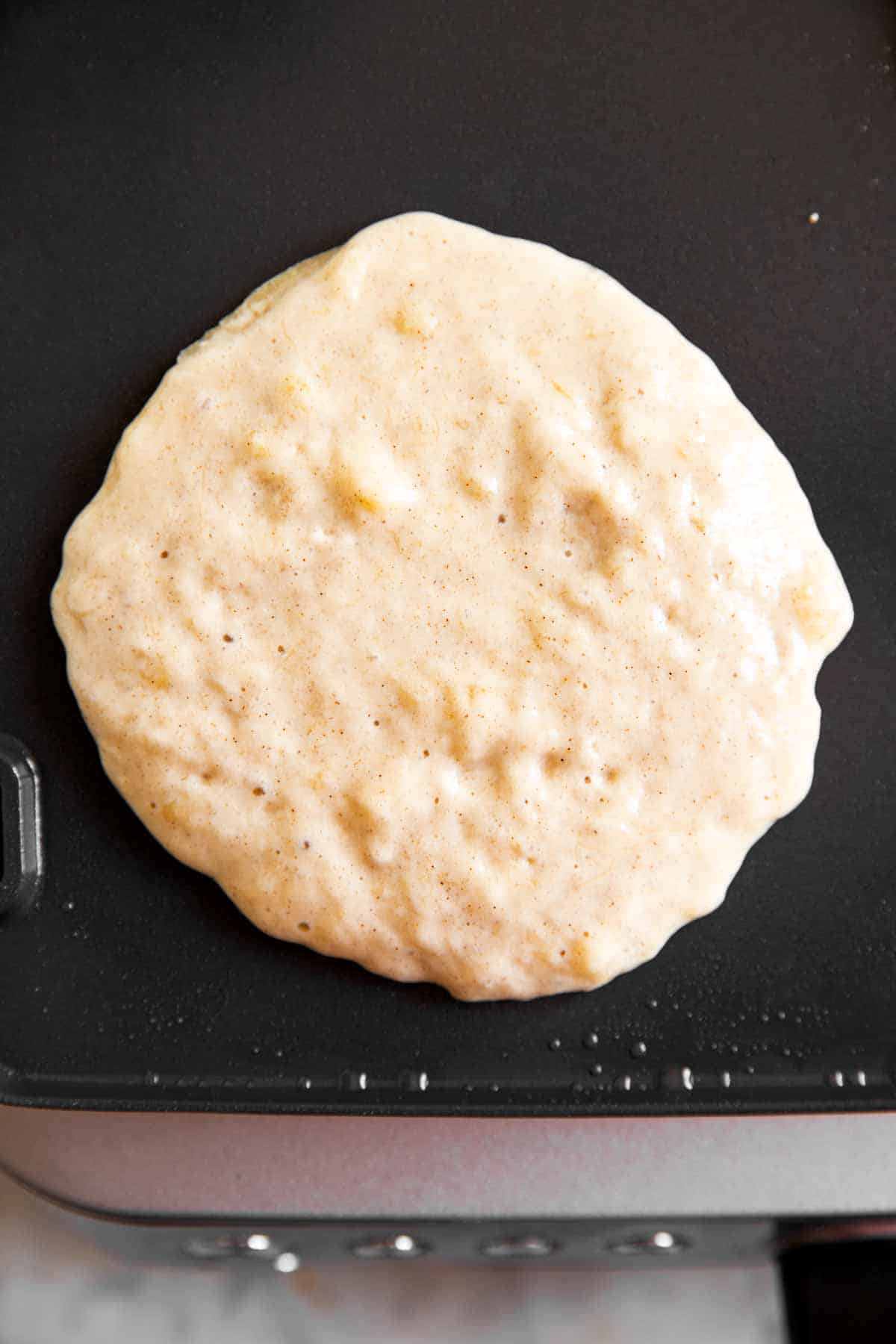 uncooked banana pancake on black griddle