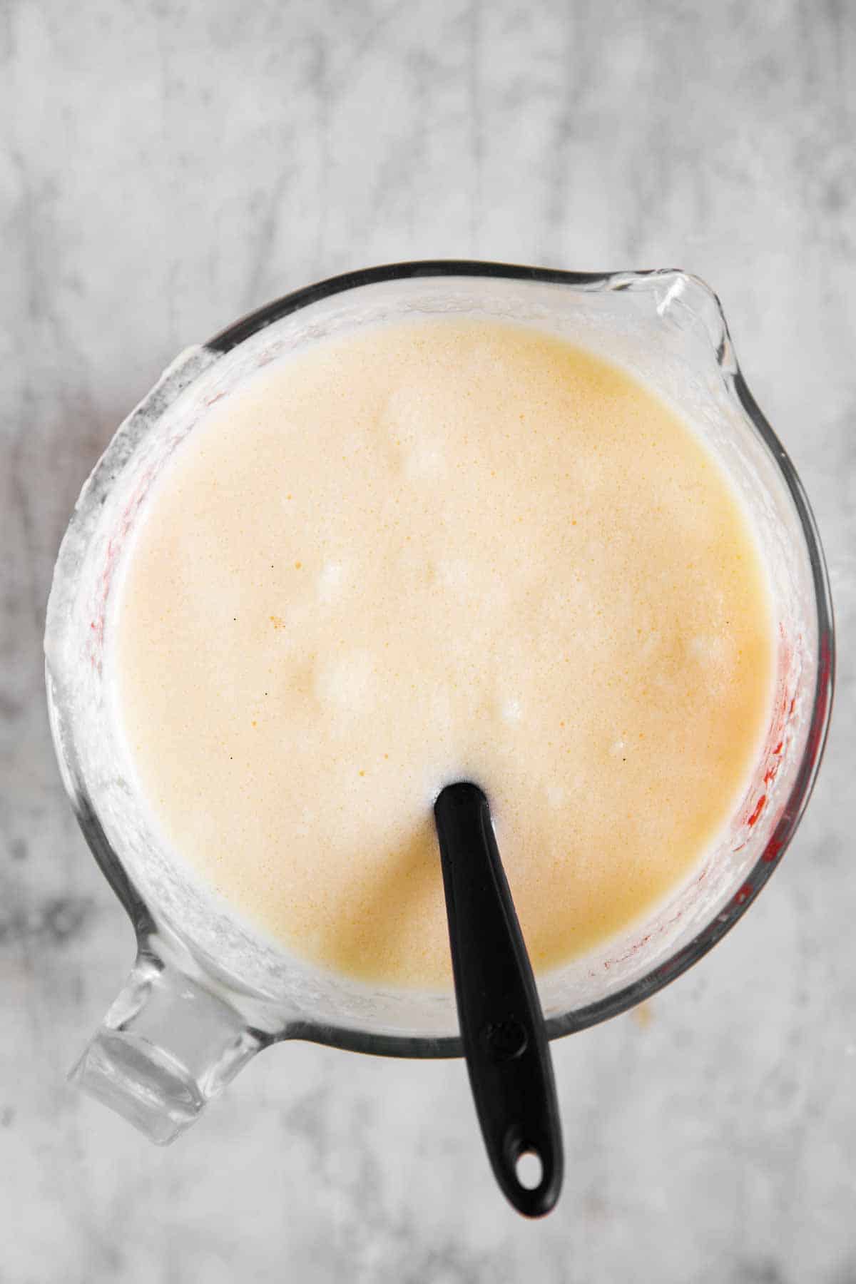 wet ingredients for buttermilk pancakes and glass bowl with rubber spatula