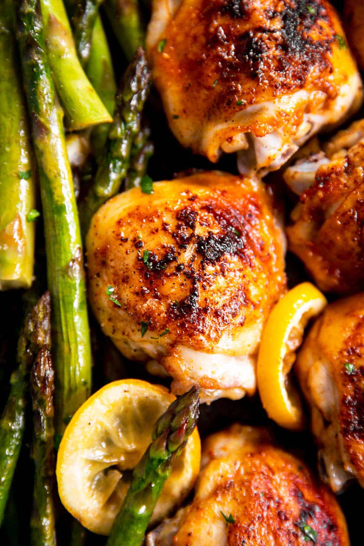 close up photo of chicken thighs and asparagus roasted with lemon