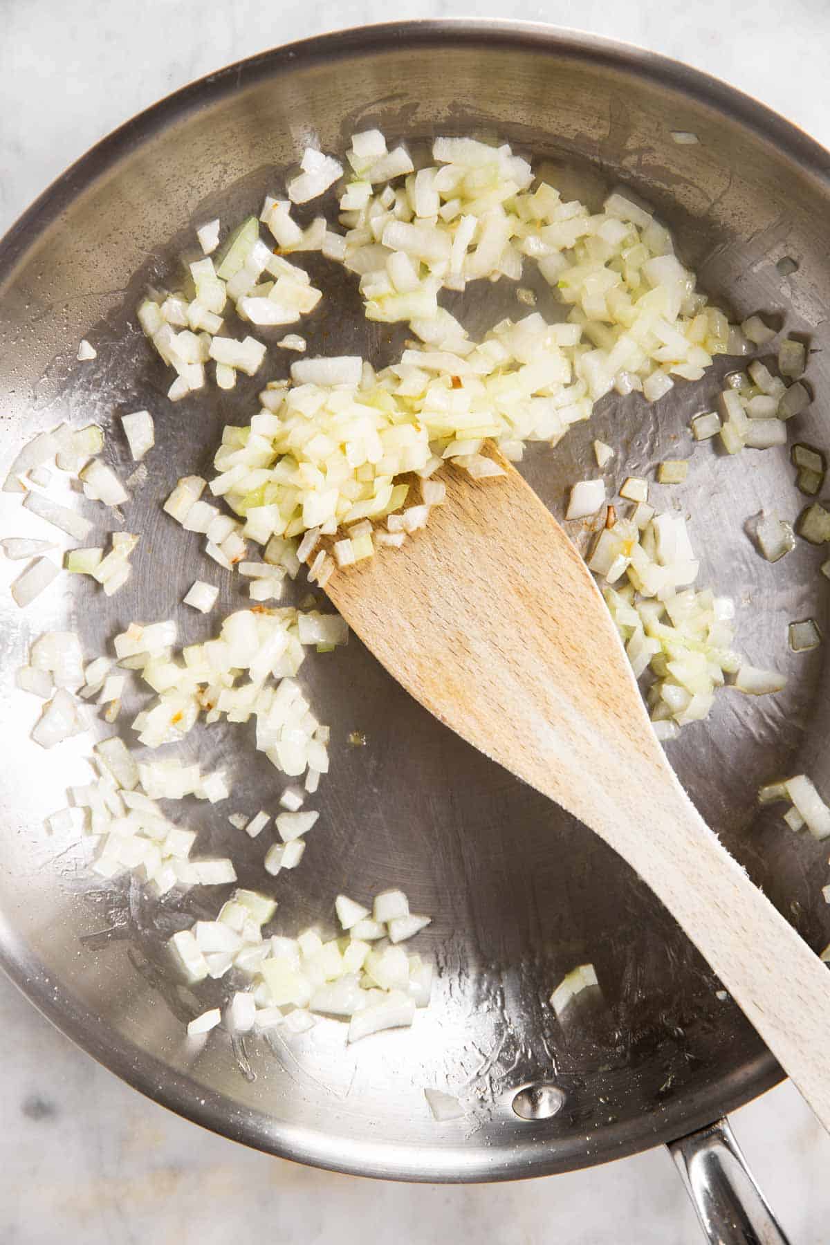 cooked onion in skillet with wooden cooking spoon