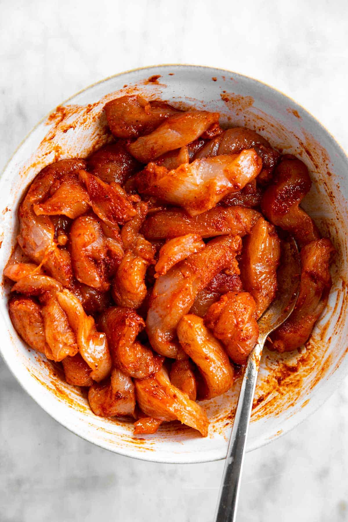 sliced chicken breast in white bowl with fajita seasoning