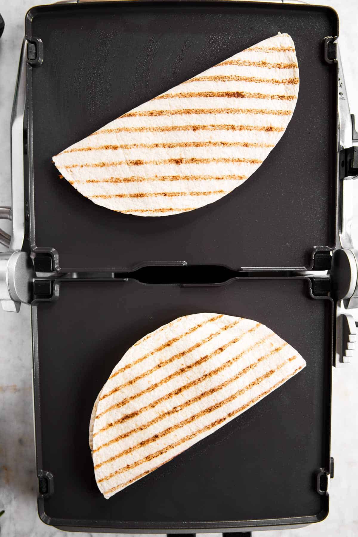 griddle with two quesadillas cooking