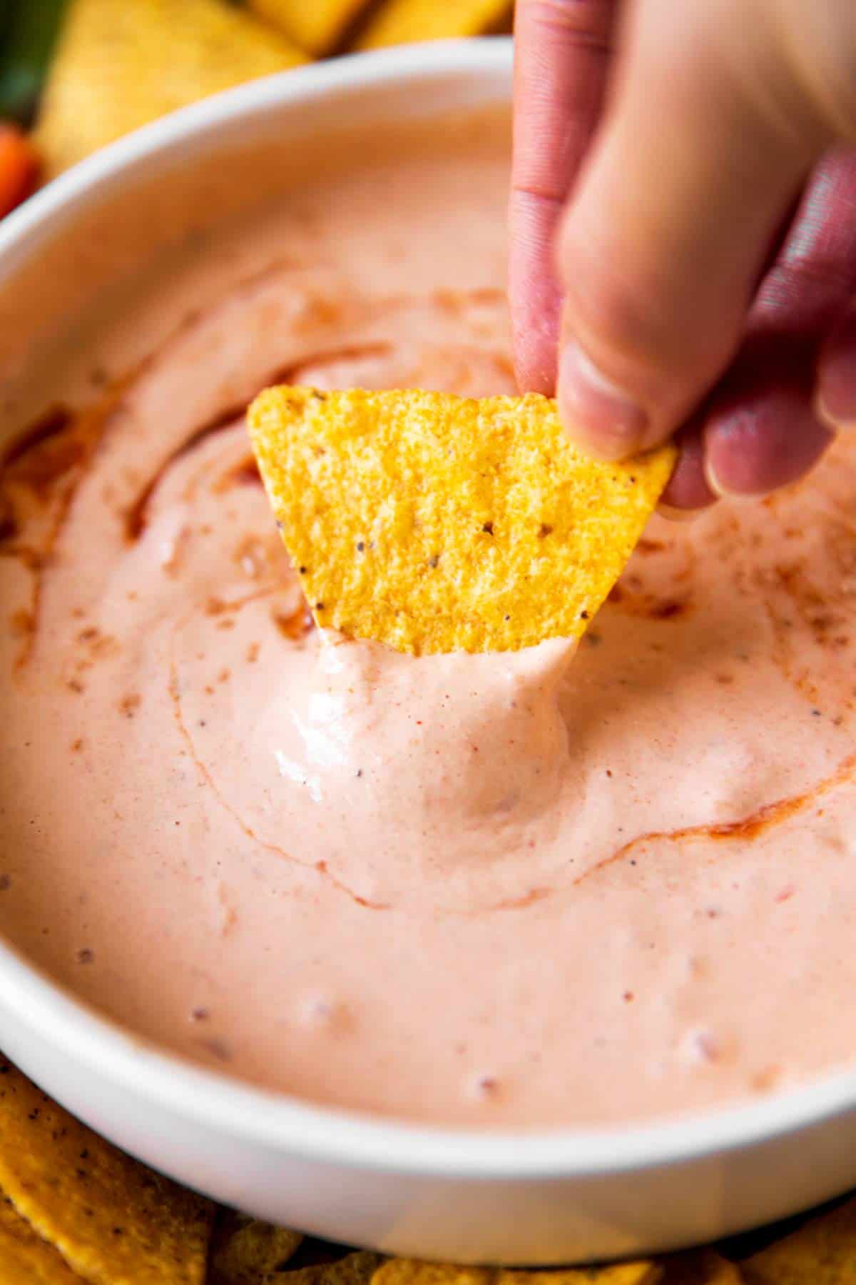 female hand dipping corn chip into chipotle mayo
