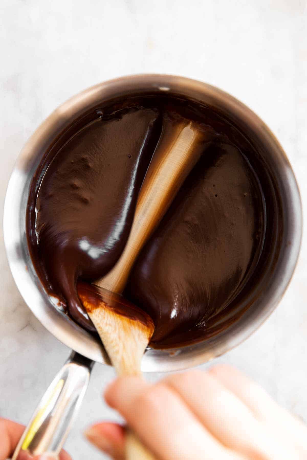 female hand stirring chocolate sauce in saucepan