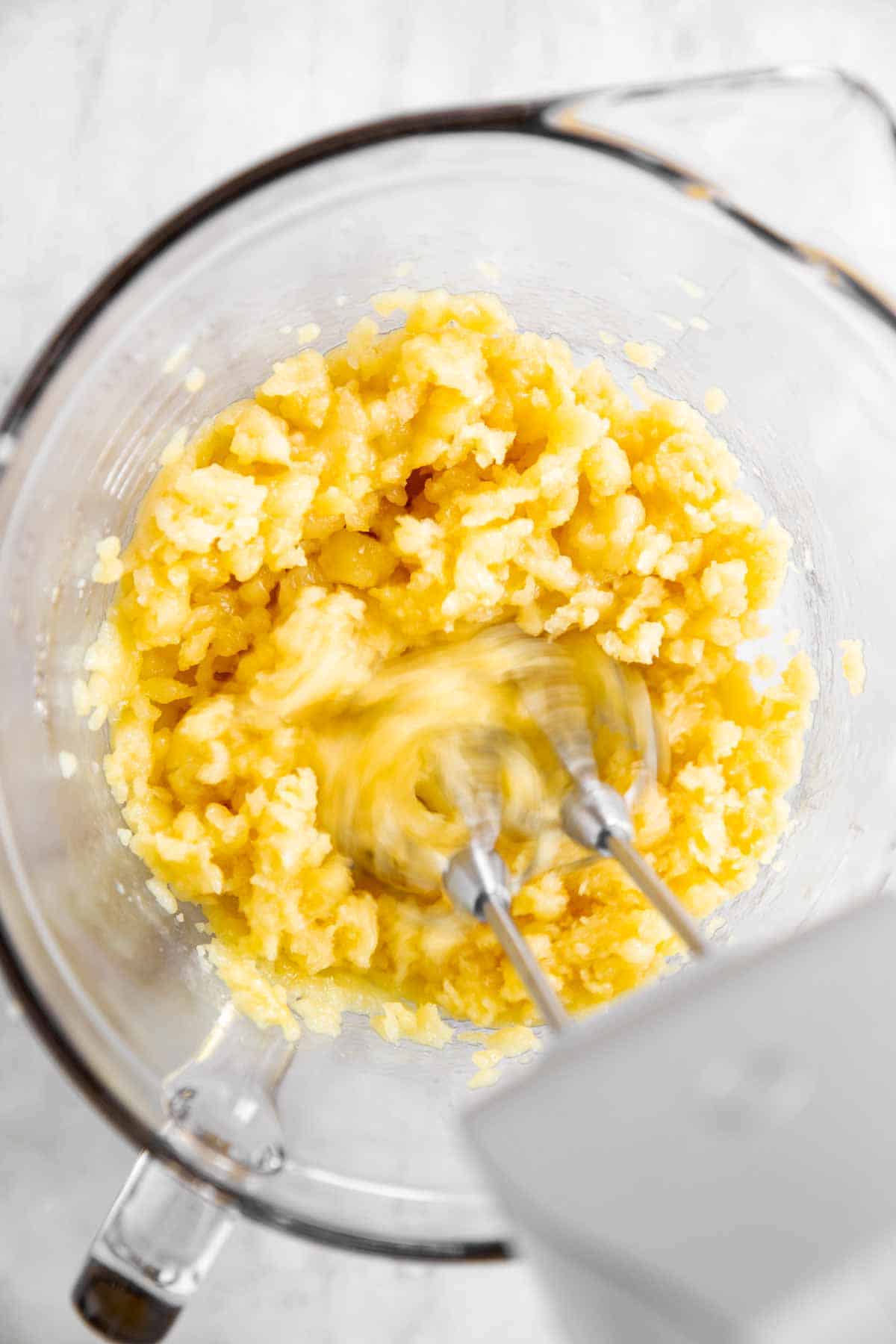 mixer mixing egg into choux pastry in glass bowl