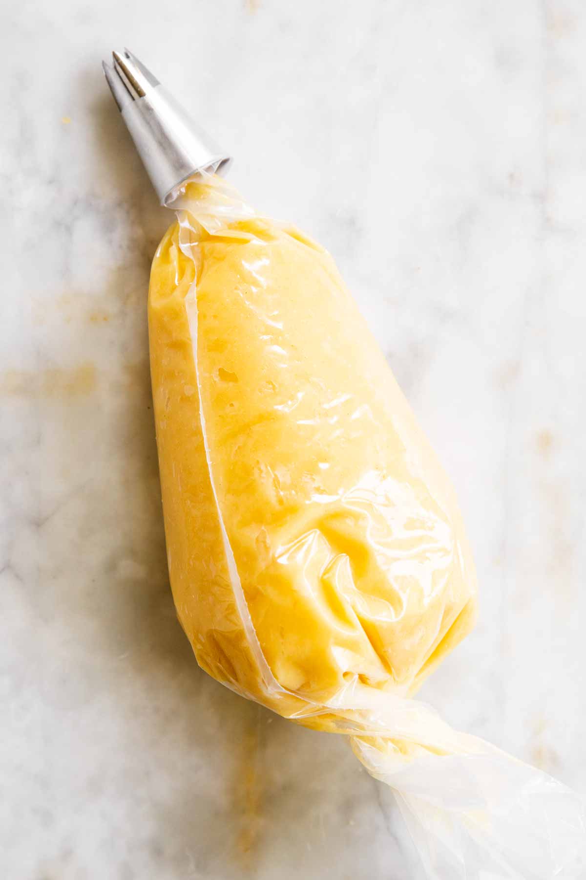 piping bag filled with choux pastry on marble surface