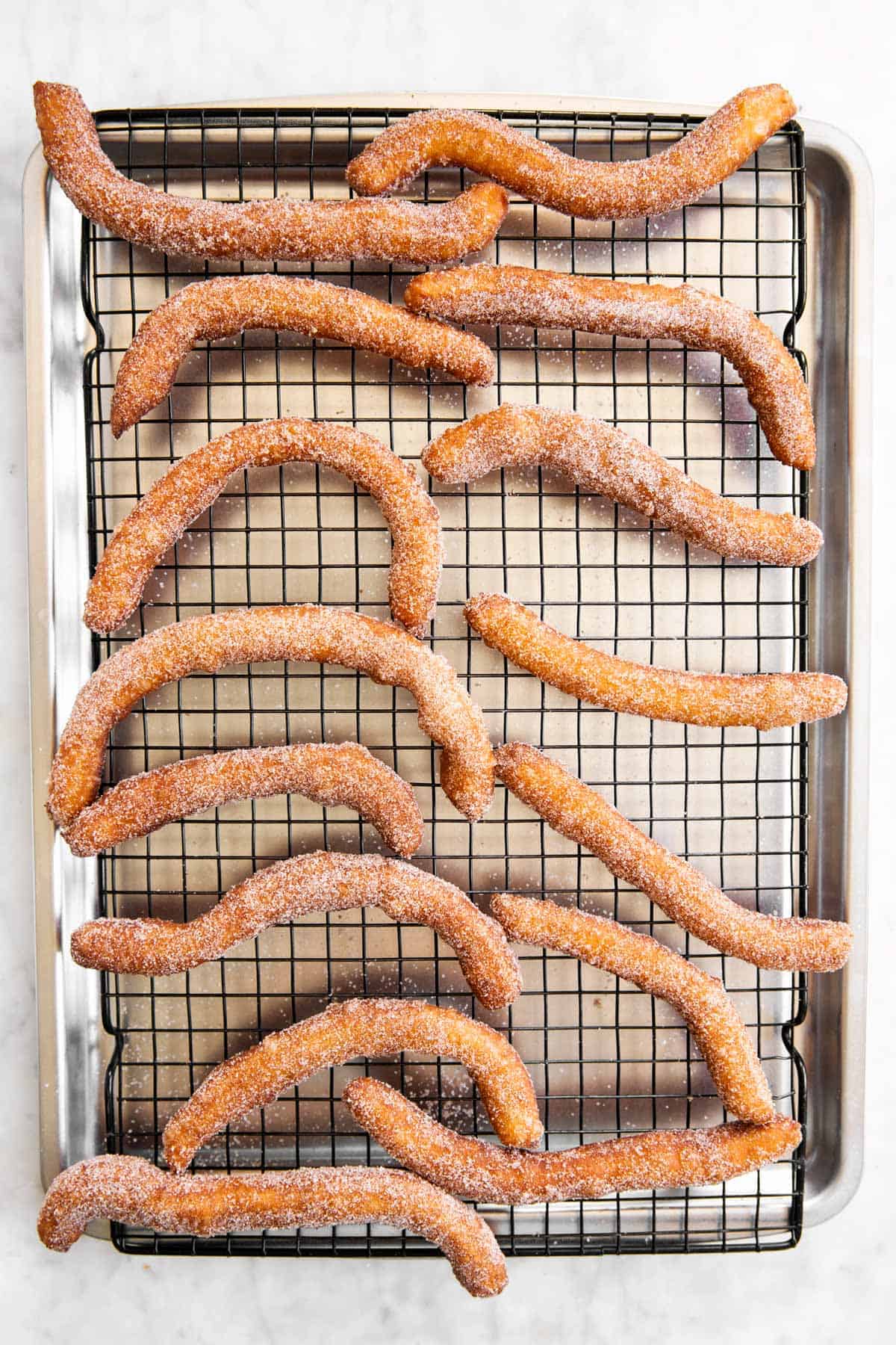 churros on cooling rack set over a metal baking pan