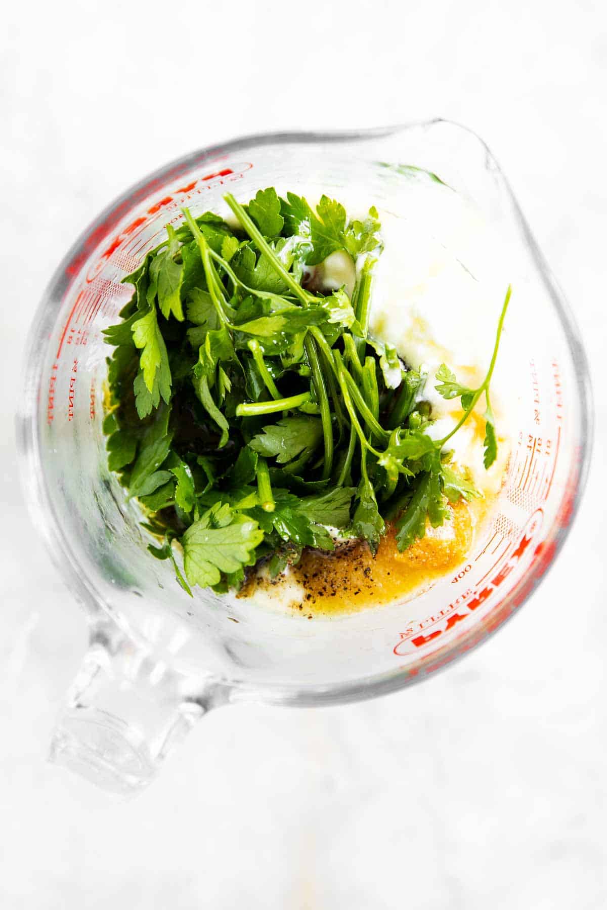 ingredients for cilantro lime dressing in glass measuring jug