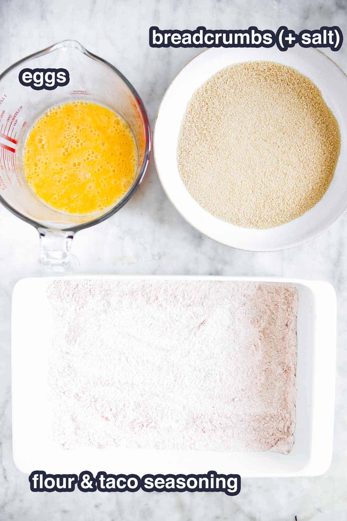 three bowls with ingredients for breading shrimp on marble surface