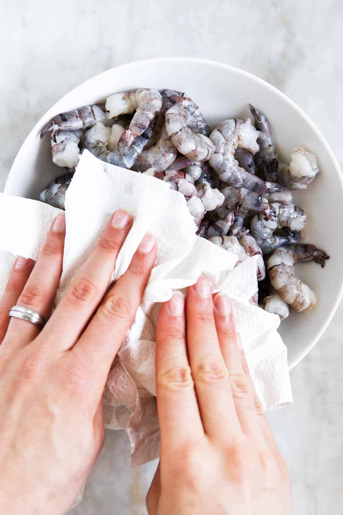 female hands drying off shrimp with paper towels