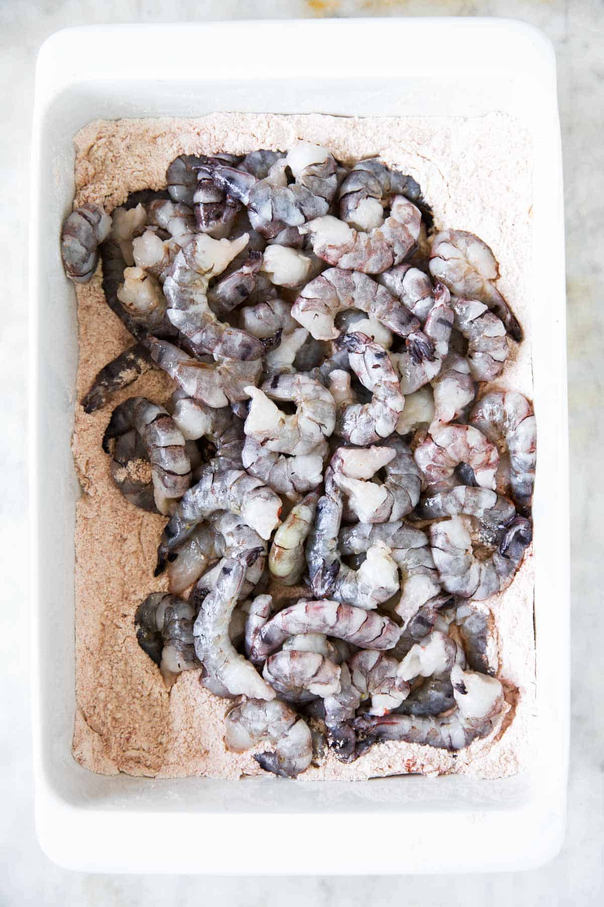 raw shrimp in casserole dish with seasoned flour