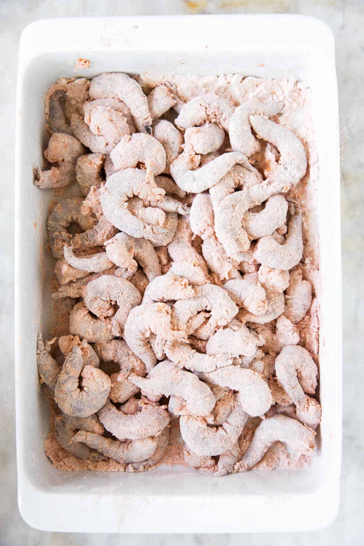 flour and seasoning coated shrimp in white casserole dish