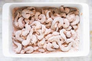 flour and seasoning coated shrimp in white casserole dish