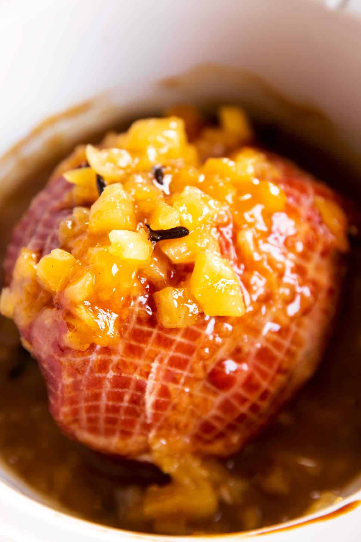close up photo of cooked ham with brown sugar pineapple glaze in white crock