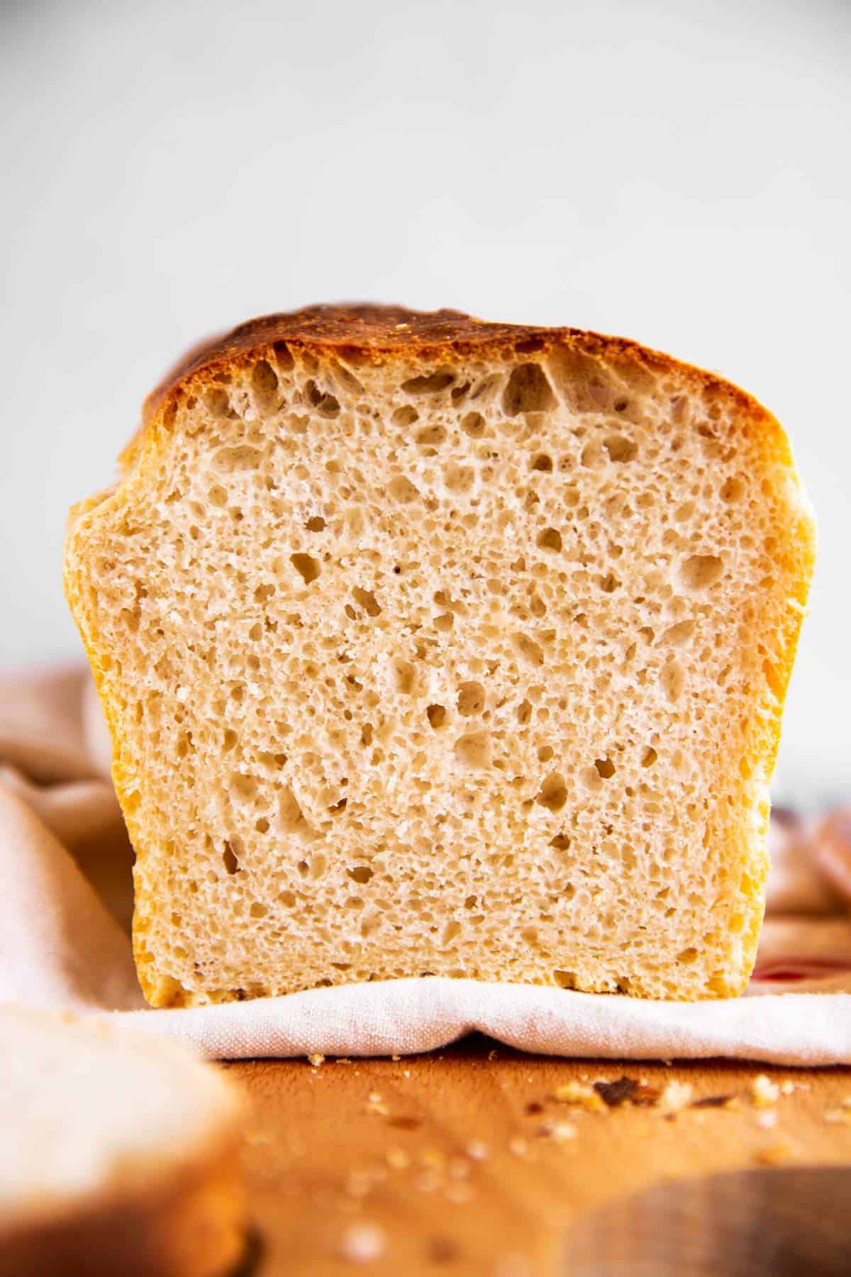 frontal view of sliced loaf of homemade sourdough bread on wooden board