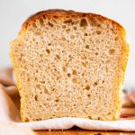 frontal view of sliced loaf of homemade sourdough bread on wooden board