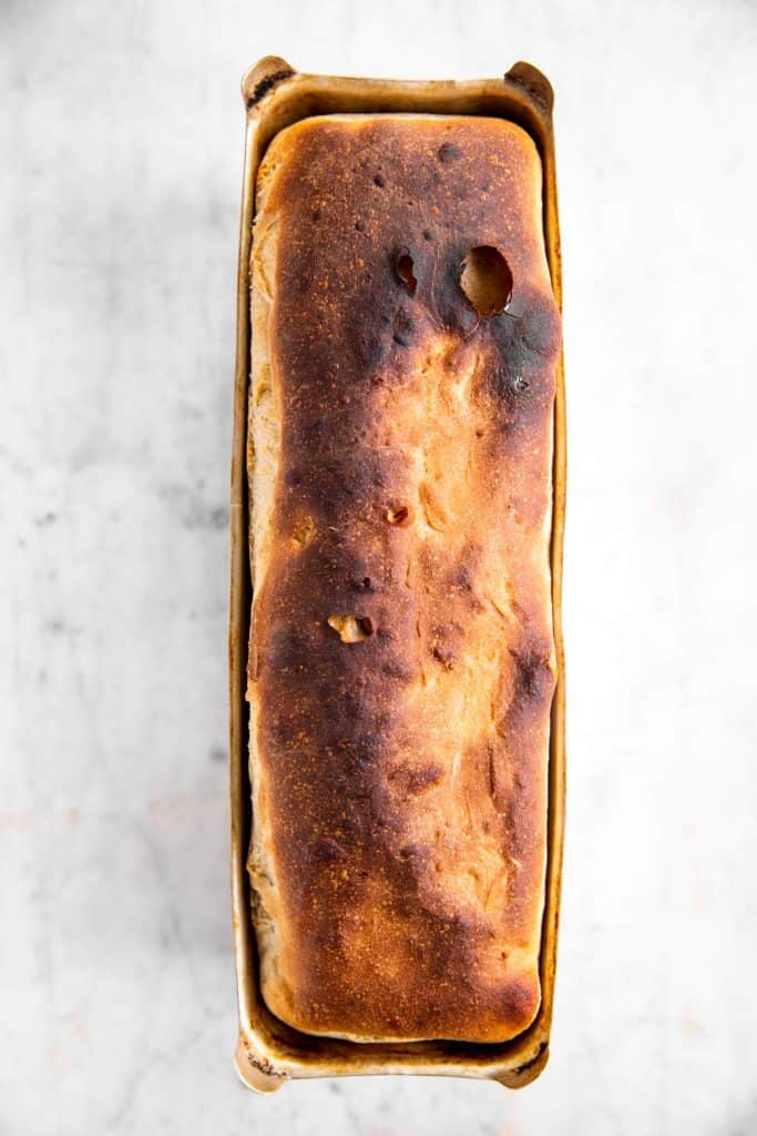 baked sourdough bread in pan on marble surface