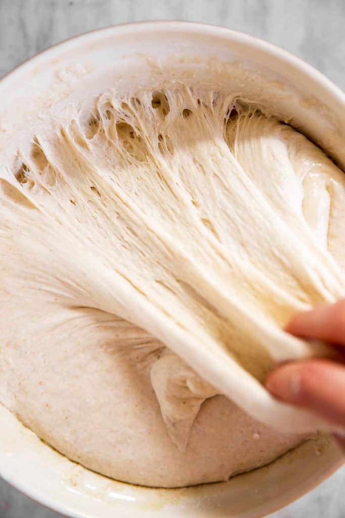 female hand pulling sourdough in white bowl