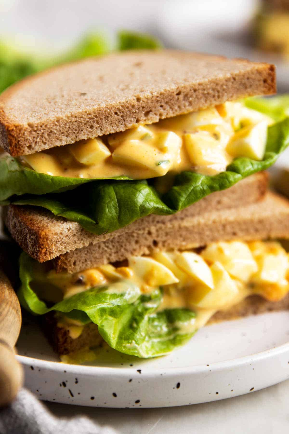 stack of egg salad sandwiches with lettuce on rye bread