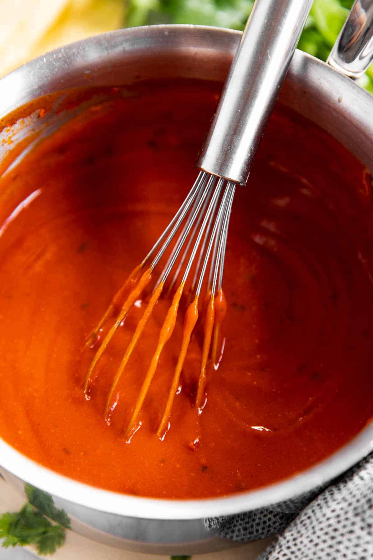 close up photo of enchilada sauce with whisk in small saucepan