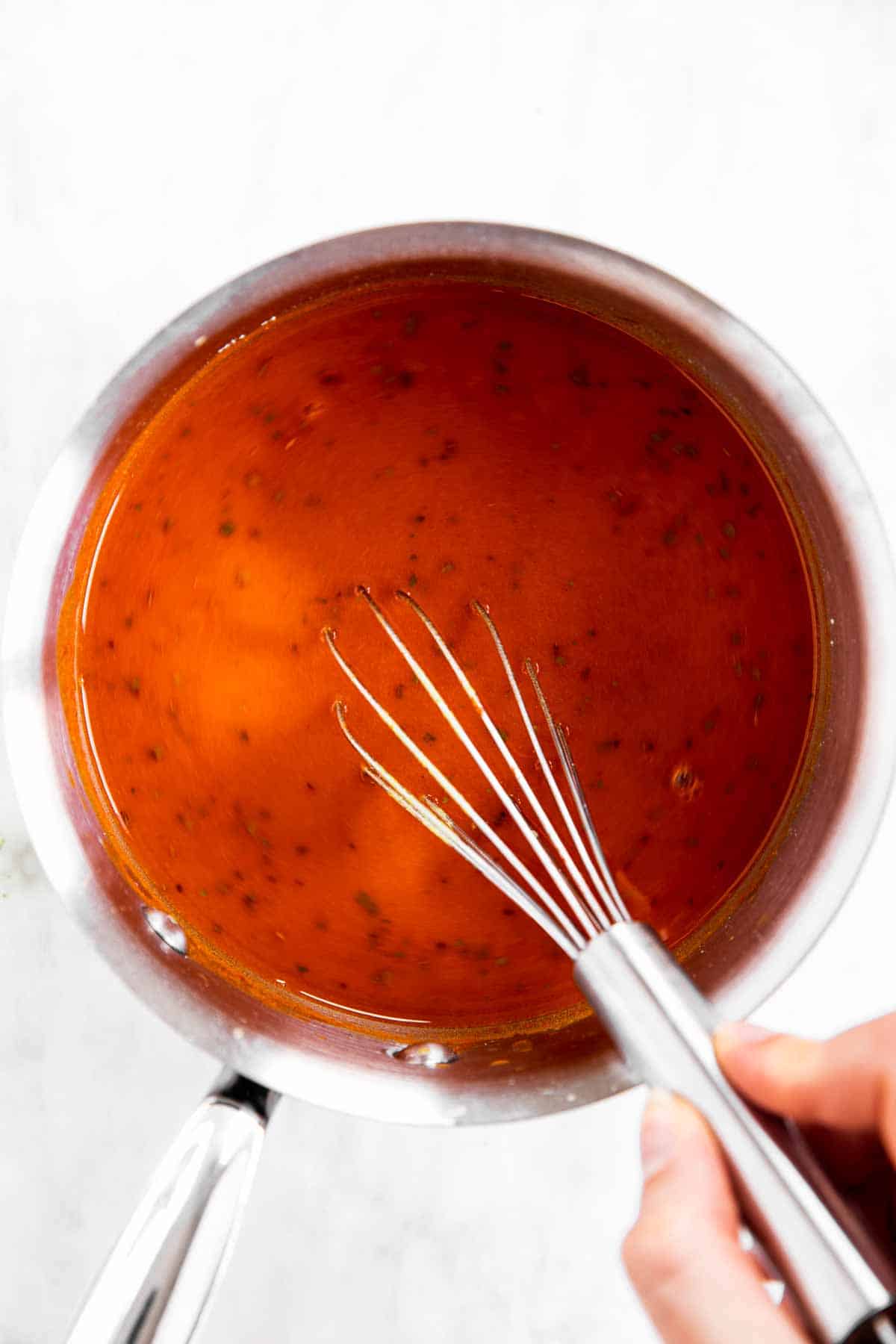 female hand whisking uncooked enchilada sauce