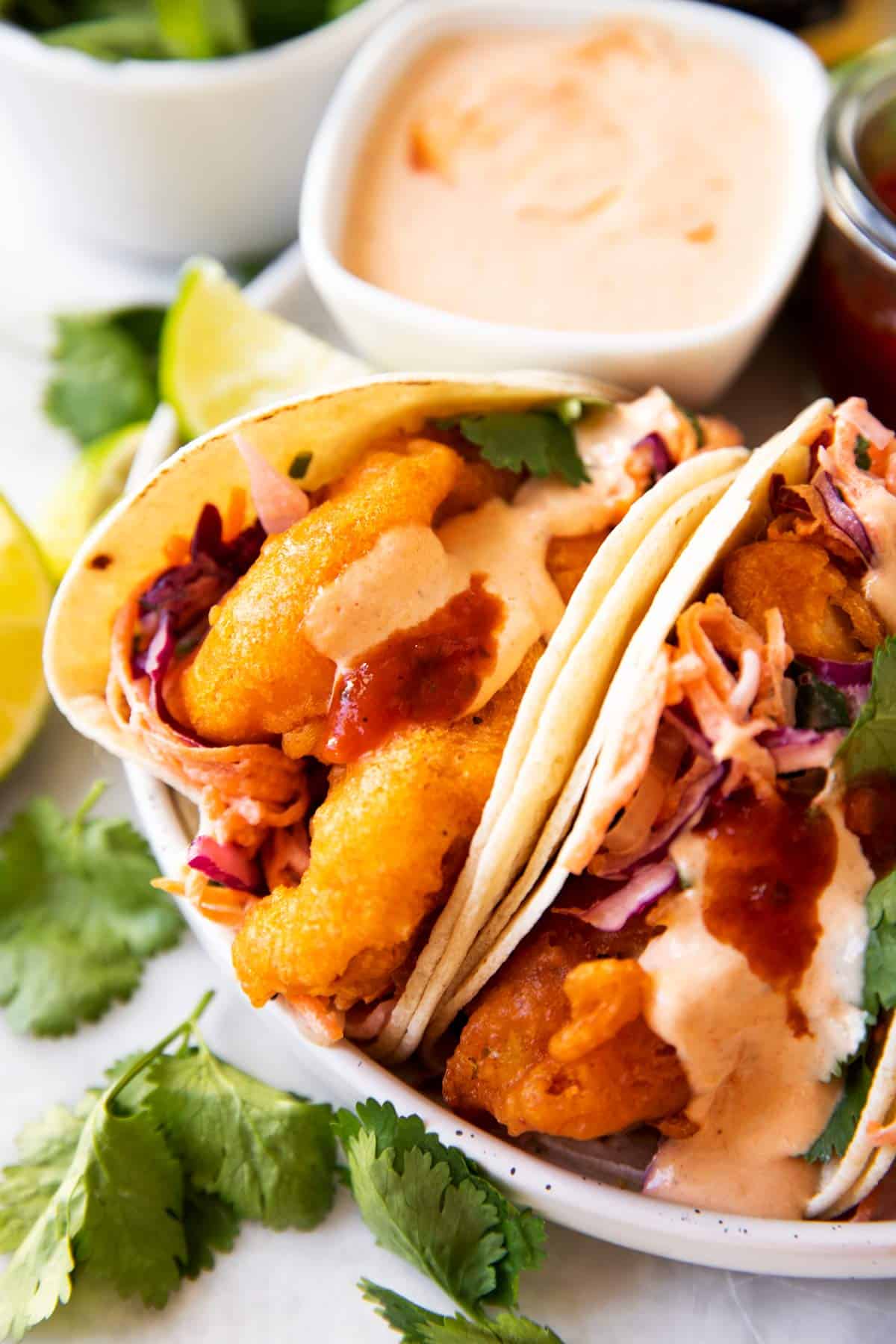 baja fish tacos on a plate with sauces in background