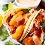 baja fish tacos on a plate with sauces in background