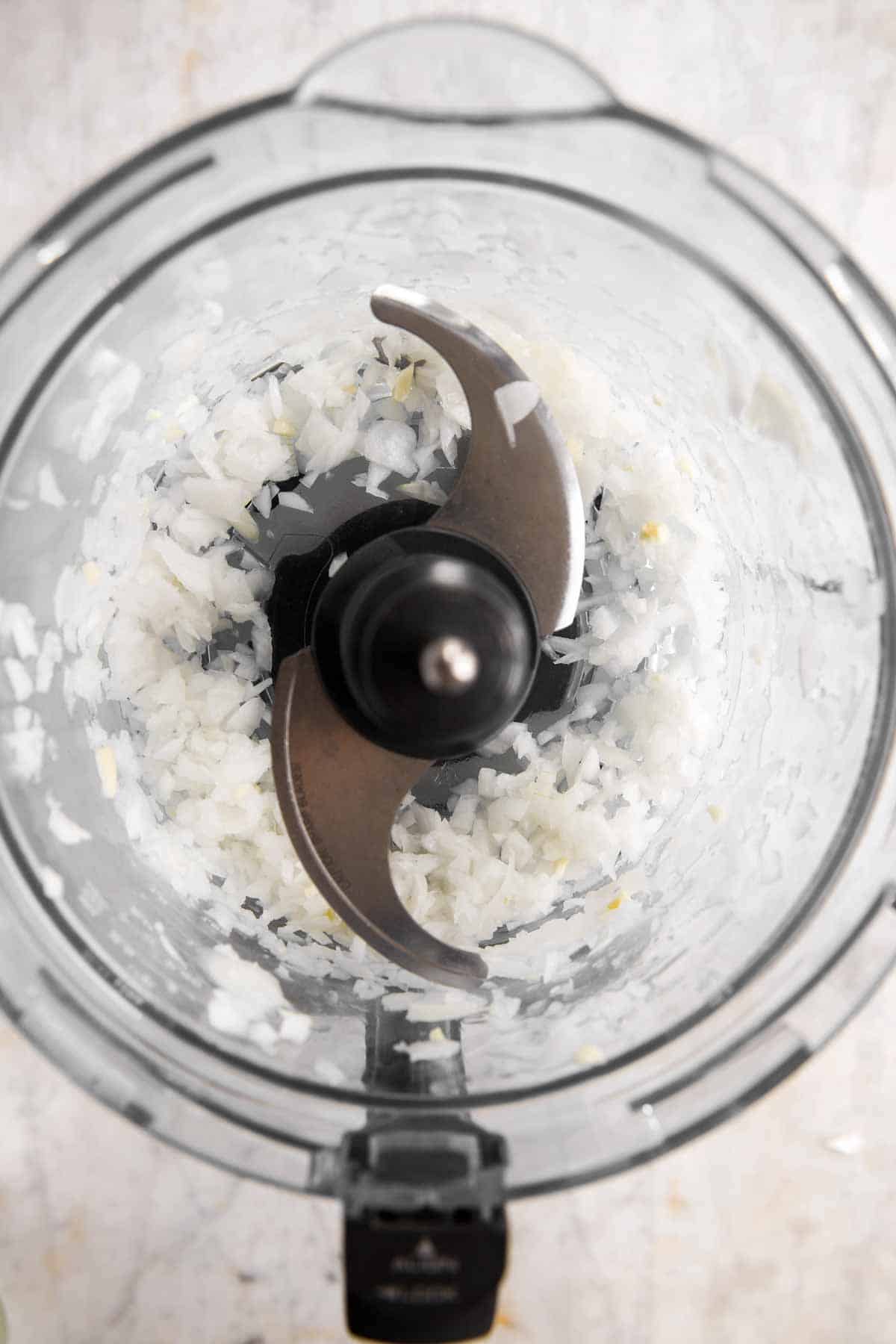 chopped onion and garlic in food processor bowl