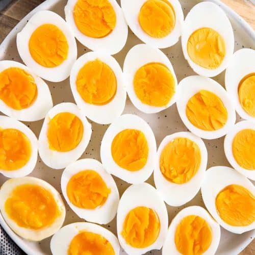 overhead closeup of white platter with hard boiled eggs cut in halves