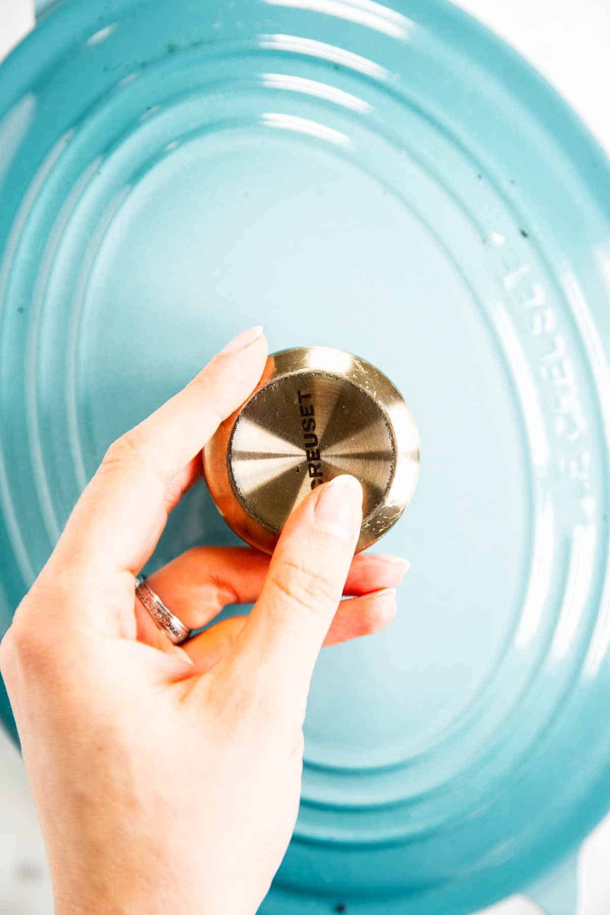 female hand holding blue Dutch oven lid