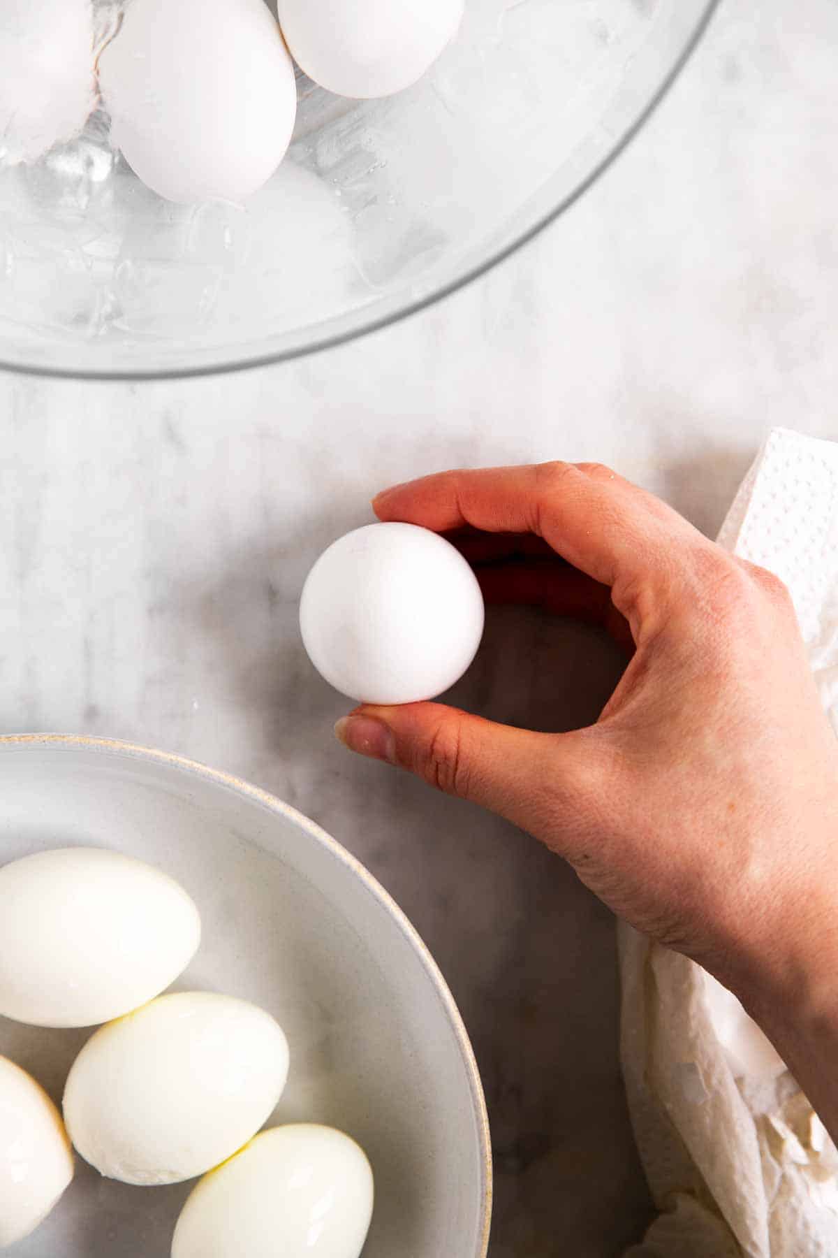 female hand holding boiled egg on marble surface