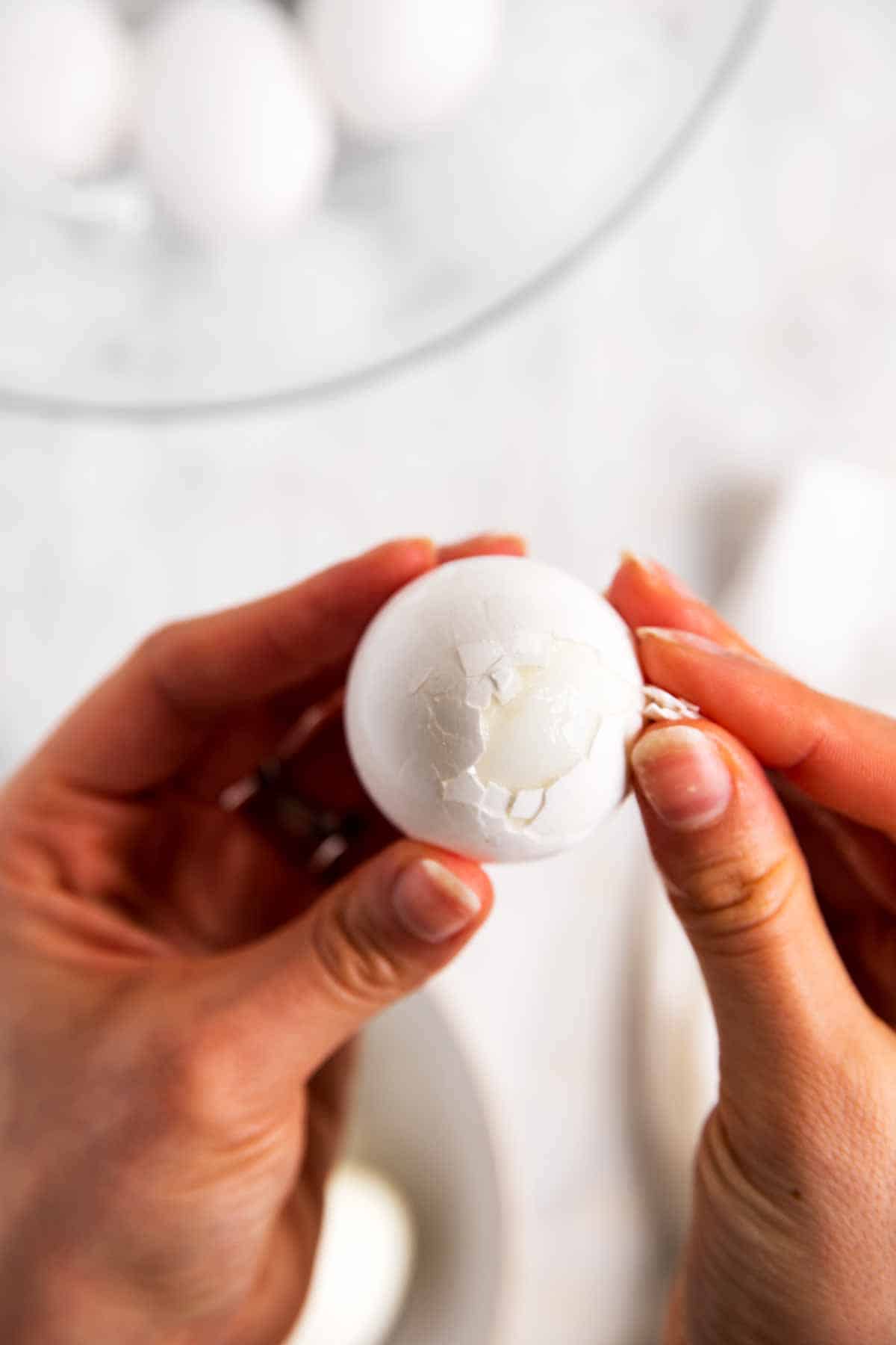 female hand peeling hard boiled egg