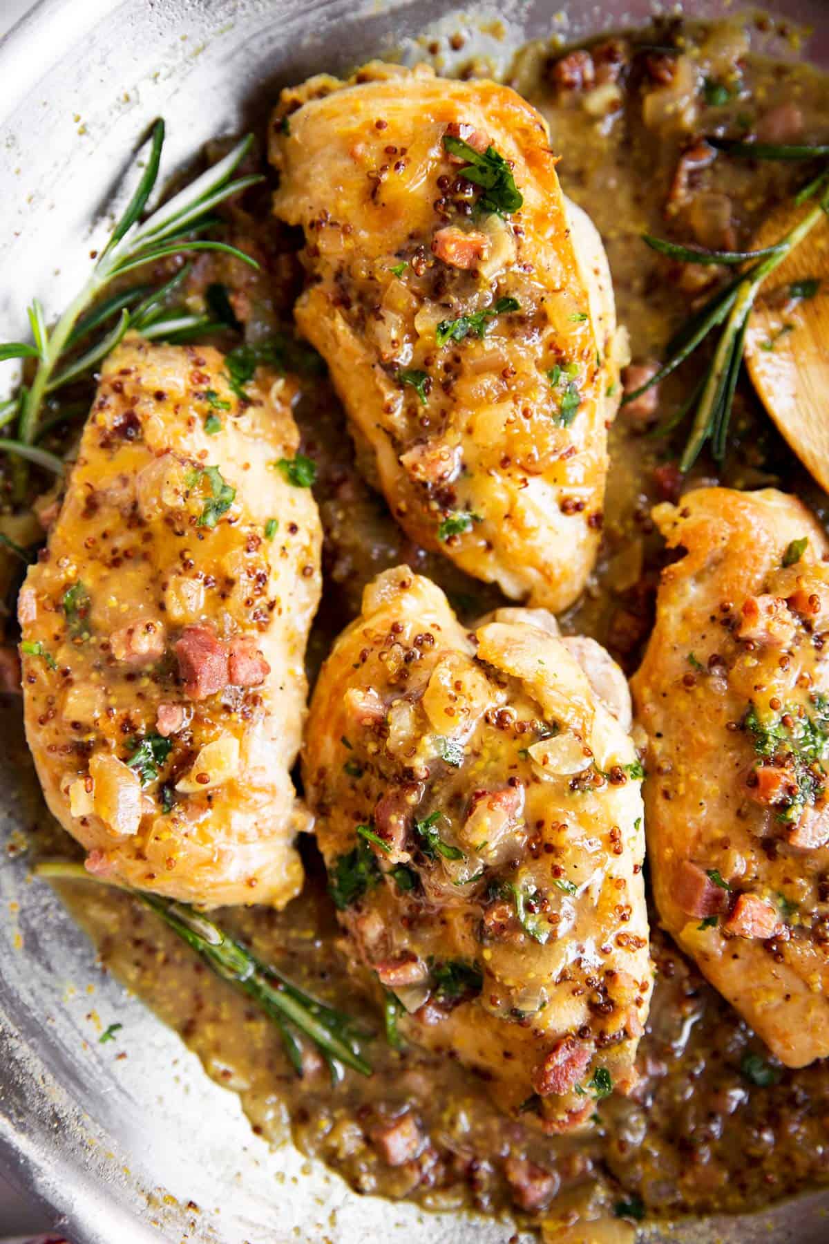 overhead close up view of four chicken breasts in honey mustard sauce in stainless steel skillet