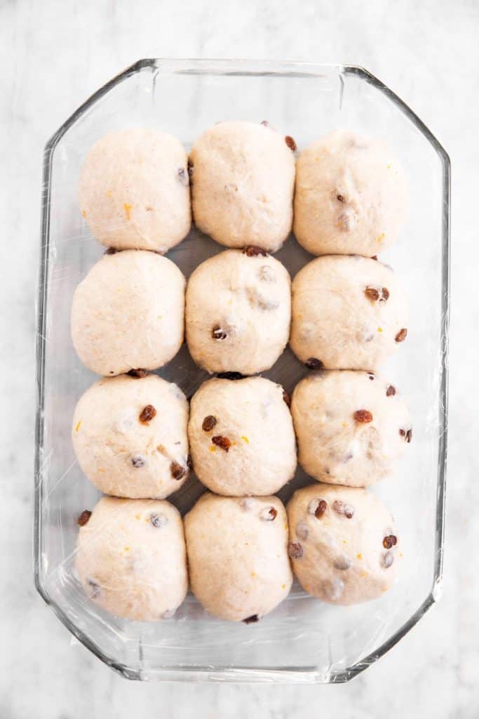 unbaked hot cross buns in glass pan after third rise