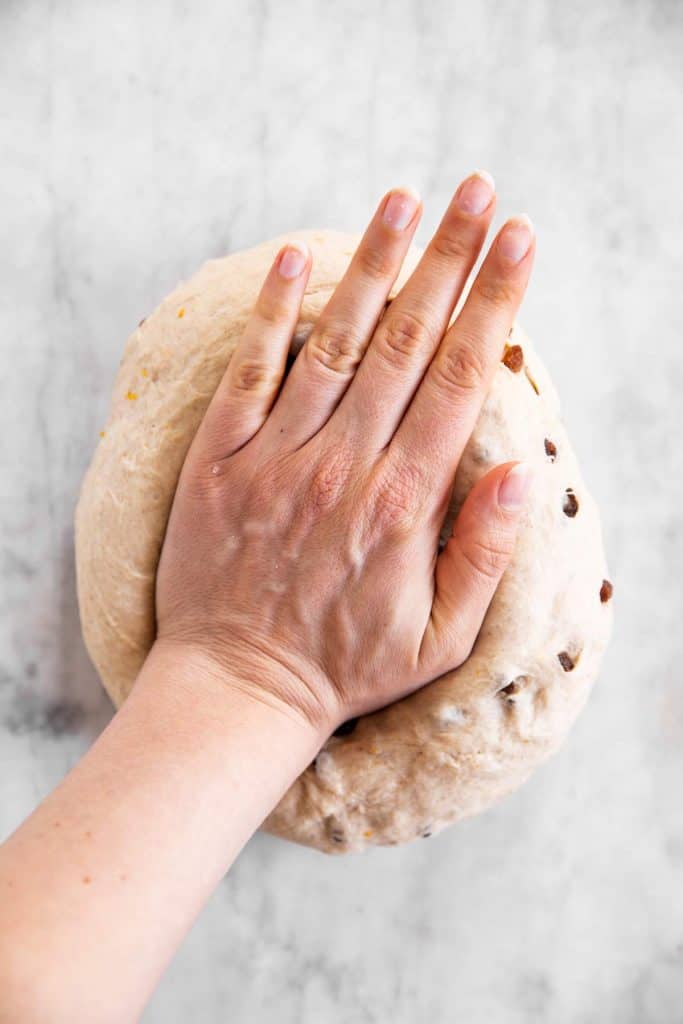 female hand kneading hot cross bun dough