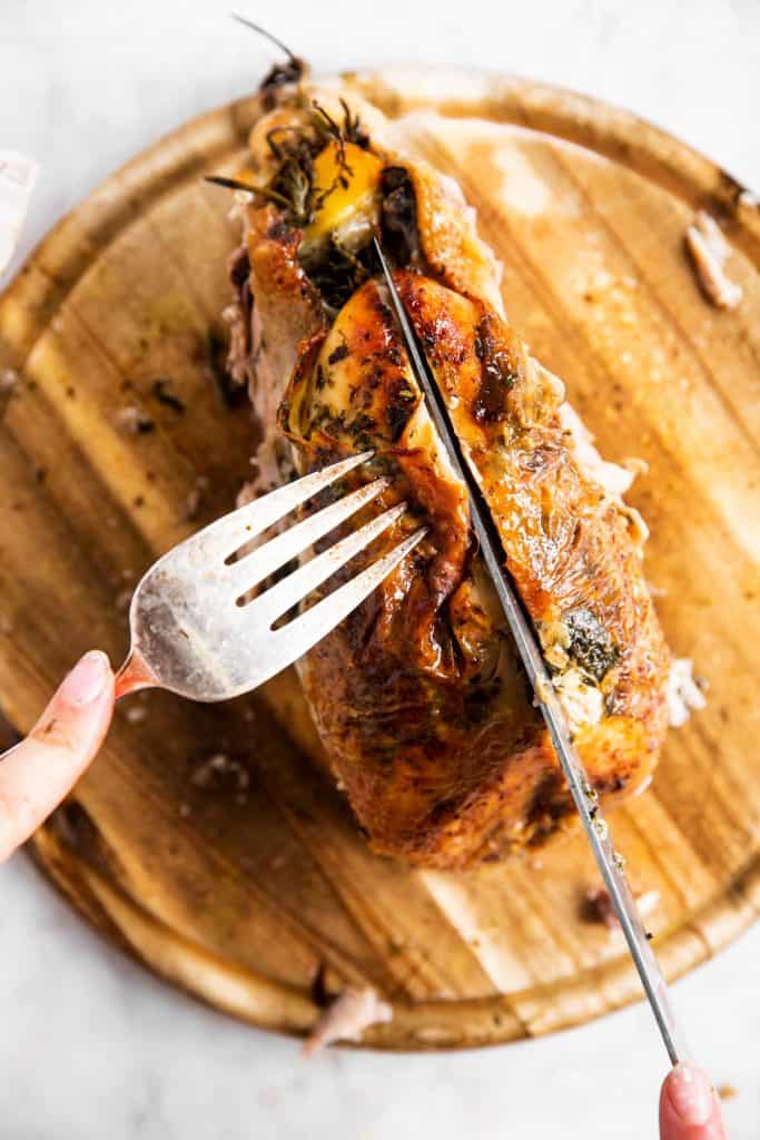 slicing apart the breast on a whole roasted chicken that's almost fully carved