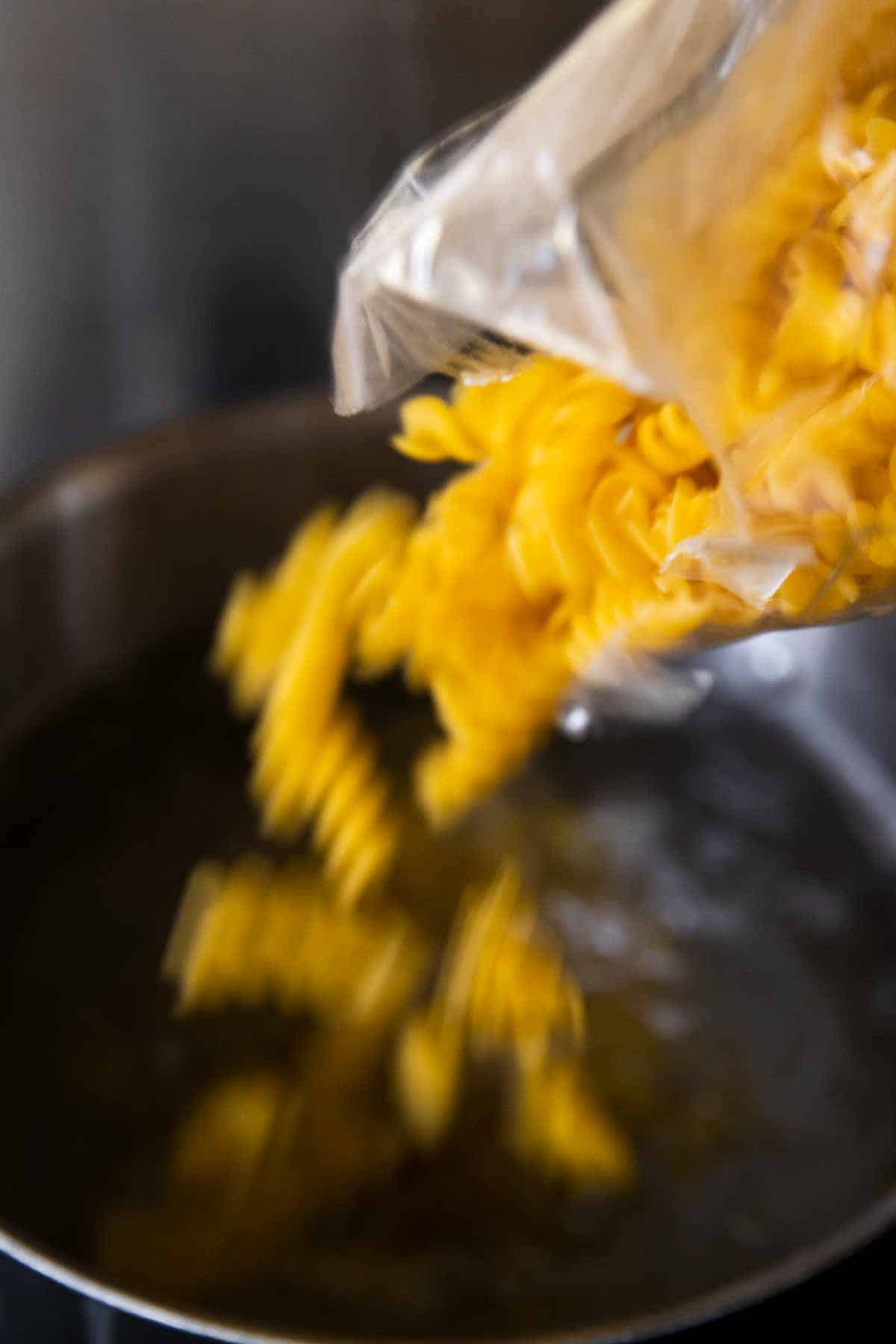 pasta pouring into pot of boiling water