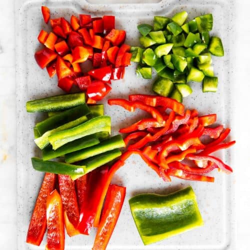 grey chopping board with red and green sliced bell pepper