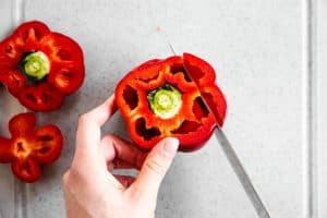 female hand slicing cheeks off a bell pepper