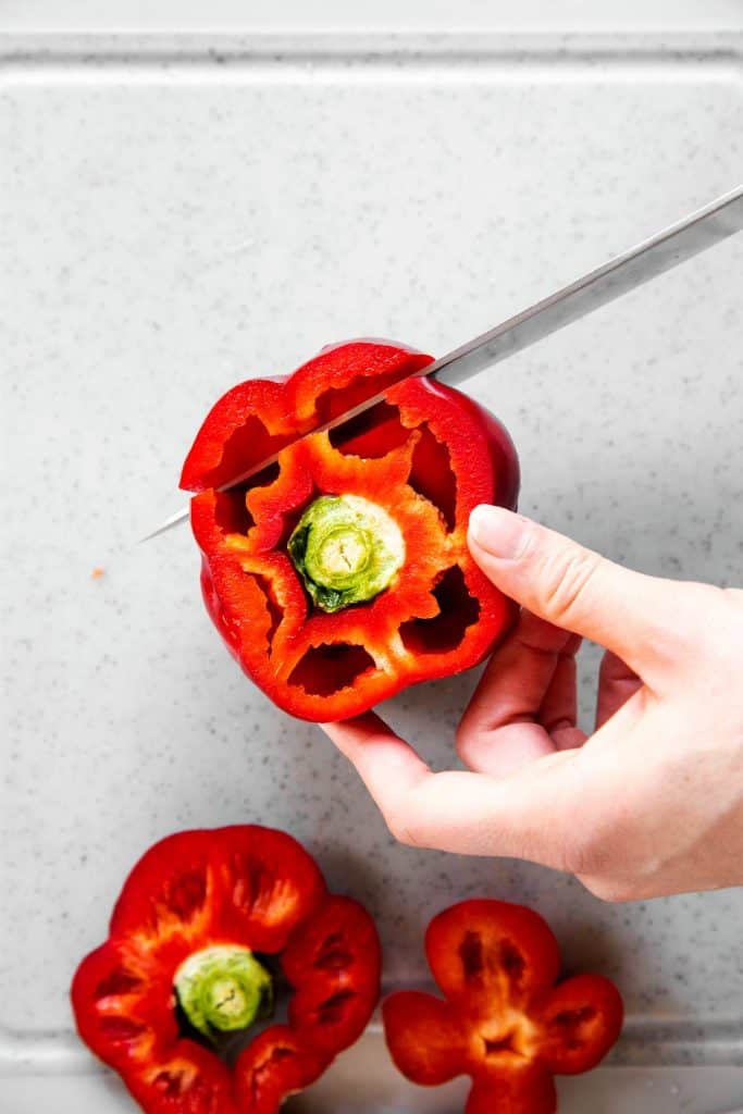 female hand slicing cheeks off a bell pepper