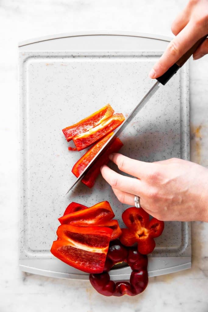 female hands slicing bell pepper into sticks