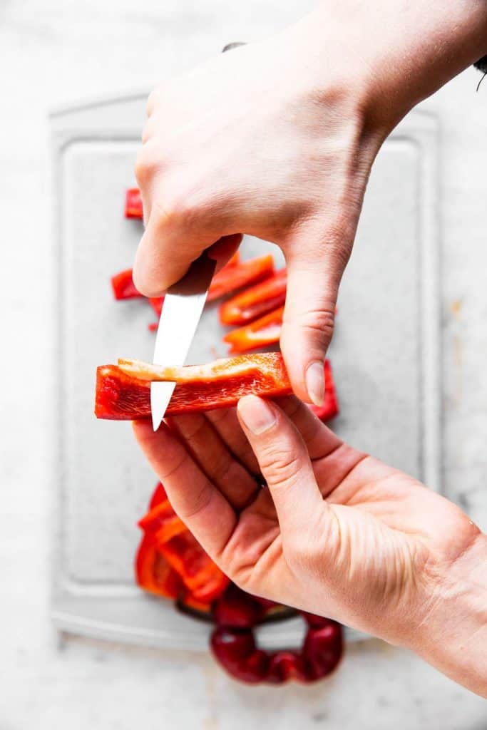 female hand trimming bell pepper stick