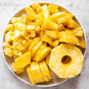 white plate filled with cut up pineapple in different shapes