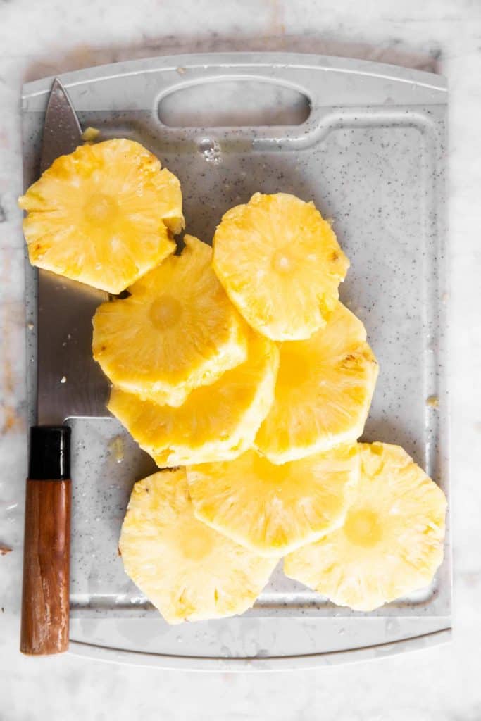 pile of pineapple rounds on grey chopping board