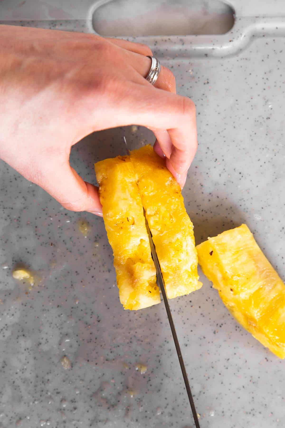 female hand cutting pineapple spears