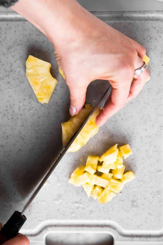 female hand slicing pineapple slices in half