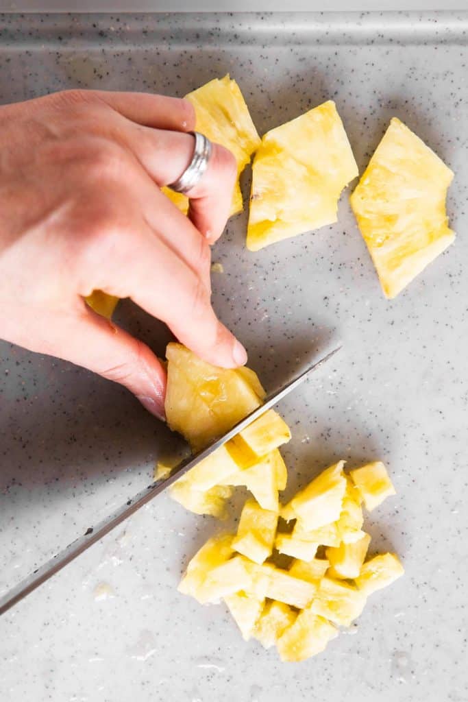 female hand finely dicing pineapple