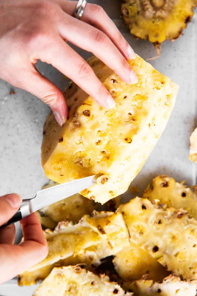 female hand removing eyes from peeled pineapple