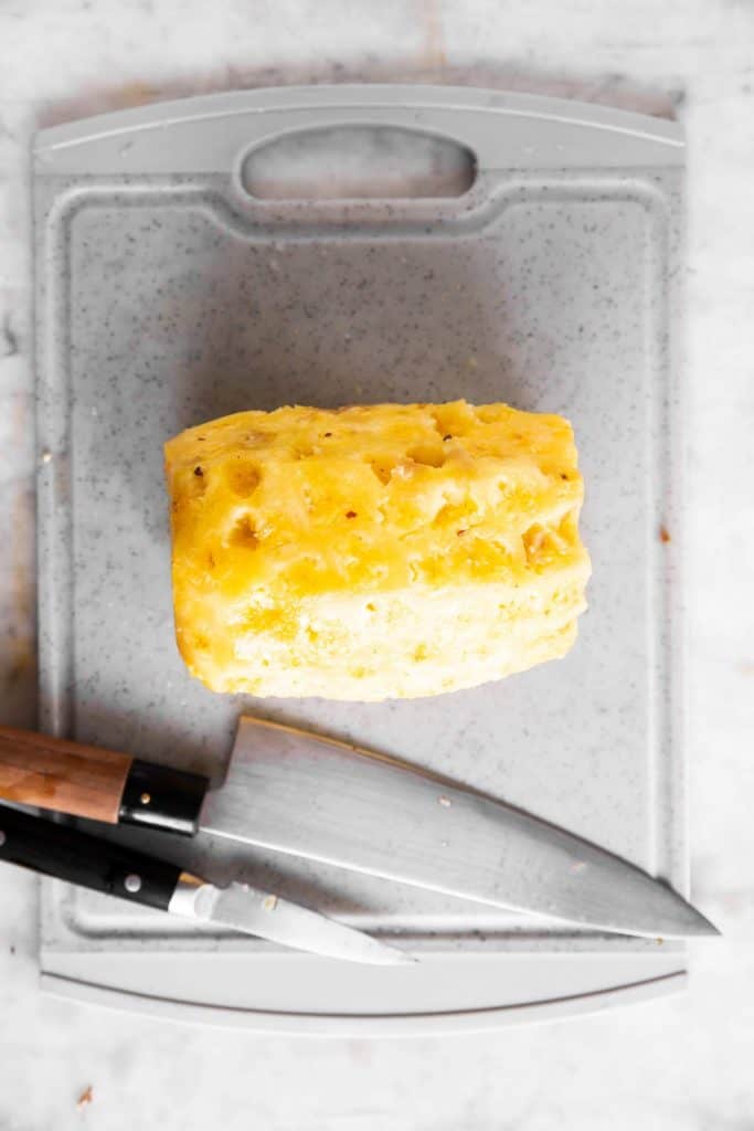 peeled and cleaned pineapple on grey chopping board