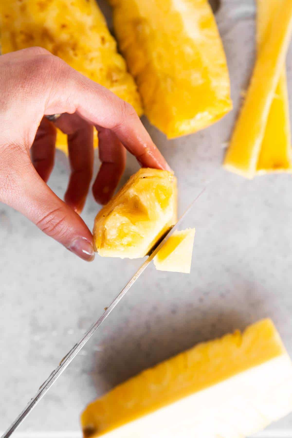 female hands slicing away core from pineapple quarter